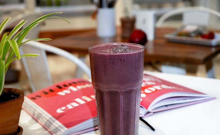 A rich, creamy blackberry smoothie served on a café table, perfect for a healthy breakfast.